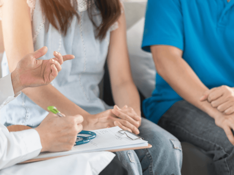 Doctor with file in hand speaking to a couple